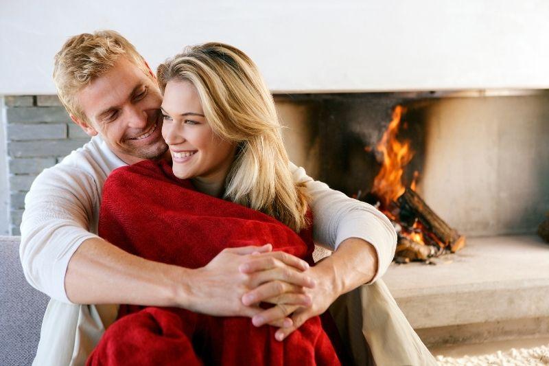adult couple cuddling inside home near the fireplace