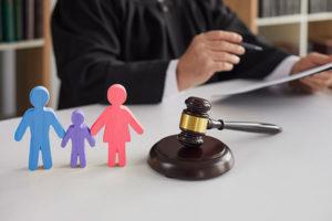 Judge reviews child custody case: wooden mother, father, and child figures on this desk