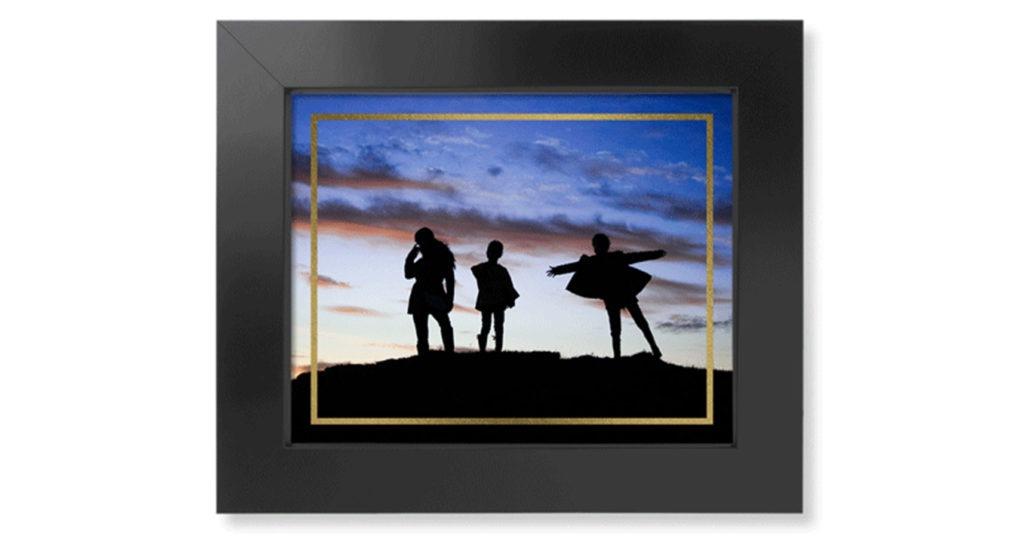 Framed art print with gold foil border around artistic photo and displayed in a dark wood picture frame